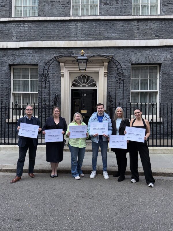 Invest in SLT campaigners, holding letter cards outside Downing Street. Left to right: • Derek Munn, Director of Policy and Public Affairs, Royal College of Speech and Language Therapists • Gillian Rudd, speech and language therapist • Sharon Oliphant, parent • Mikey Akers, founder and trustee of Mikey’s Wish Foundation • Louisa Akers, parent and trustee of Mikey’s Wish Foundation • Francesca Beard, speech and language therapist