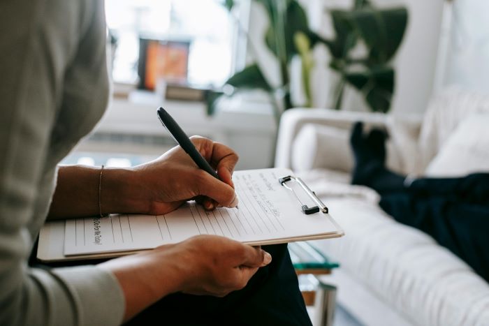 Close up image of person writing on a clipboard balanced on their knees