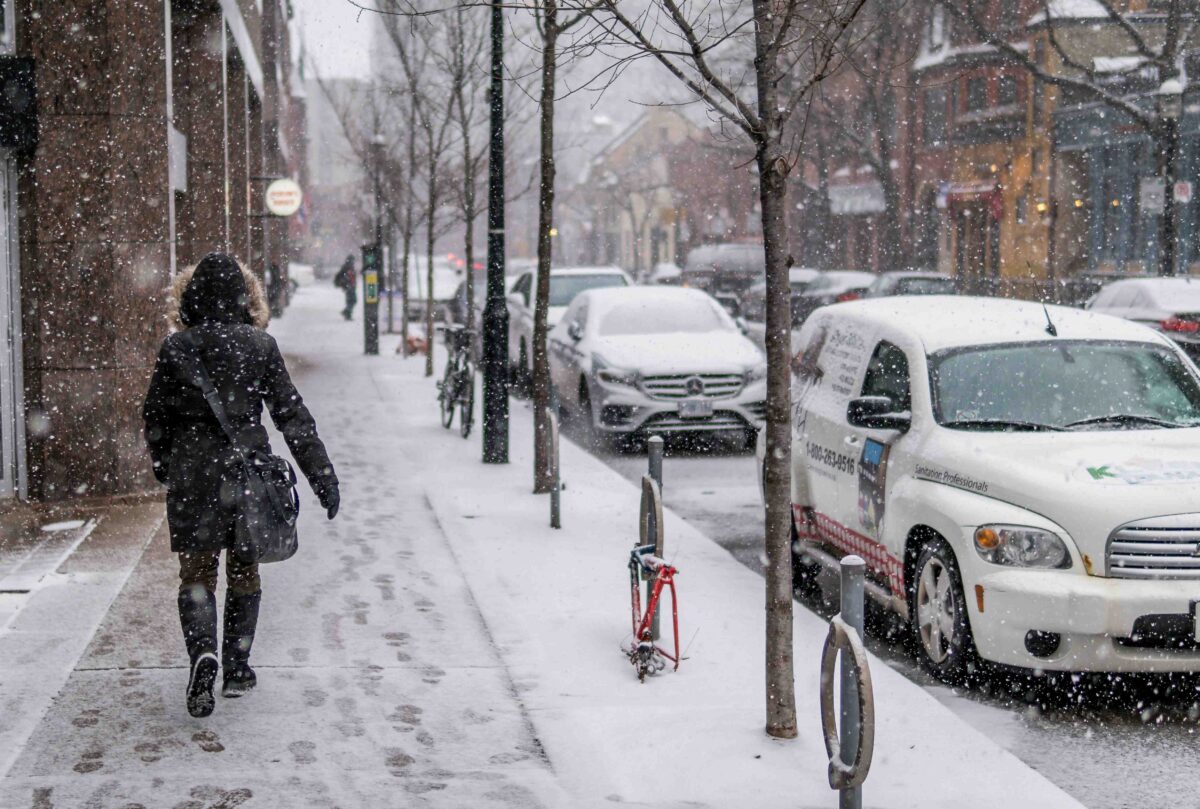 Lady walking on pavement in snow in Toronto Canada